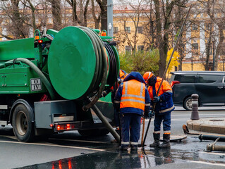 Sewer workers cleaning manhole and unblocking sewers