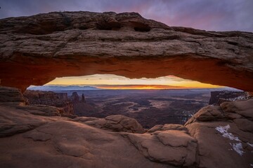 View through arch Mesa Arch at sunrise, Colorado River Canyon with the La Sal Mountains behind,...