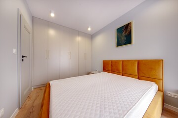 Sypialnia w nowoczesnym apartamencie z dużym  materacem i białą szafą