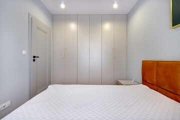 Sypialnia w nowoczesnym apartamencie z dużym  materacem i białą szafą