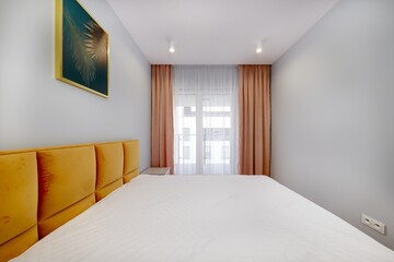 Sypialnia w nowoczesnym apartamencie z dużym  materacem i białą szafą