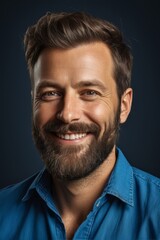 Obraz premium smiling man with beard and blue shirt on dark background