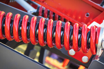 Steel red spring as part of black heavy agricultural, industrial machine. Technology