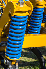 Steel blue spring as part of heavy agricultural, industrial machine. Technology