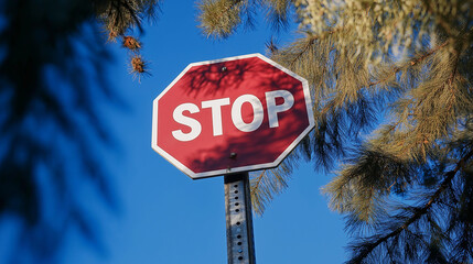 Fototapeta premium Stop sign against vivid blue sky with tree shadows. Perfect for traffic safety materials, urban photography, and municipal documentation.