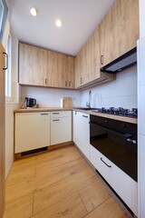 Kuchnia w nowoczesnym apartamencie w jasnych kolorach , biel,  i jasno brązowym blatem