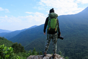 Successful woman hiker taking photo at mountain peak cliff edge
