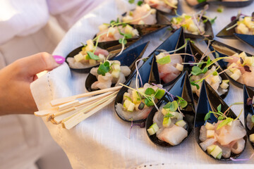 Individual servings of sea bass tartare with green apple and microgreens presented in mussel shells...