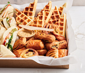 A lavish spread featuring waffles, croissants, and sandwiches arranged beautifully for a morning gathering. Ideal for social events or brunch celebrations, this display delights guests