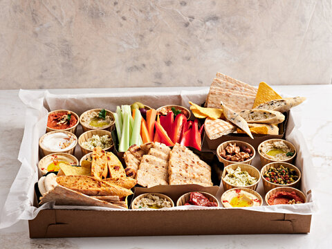A beautifully arranged platter features an array of dips, fresh vegetables, and crispy bread. Perfect for sharing at a casual gathering or party, inviting everyone to enjoy
