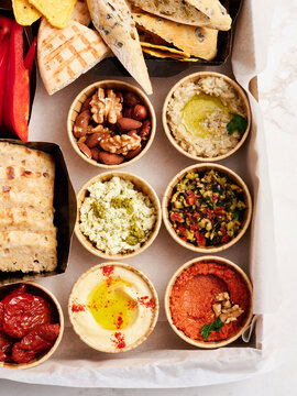 A colorful display of various dips and spreads arranged neatly on a platter includes hummus, olive tapenade, and more. Accompanied by fresh crackers and vegetables, it invites sharing