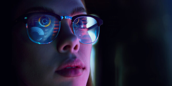 Close-up of woman wearing glasses reflecting bar charts and financial analytics, symbolizing professional focus. Concept of business, modern technologies, finance, strategy, sales, marketing, kpi