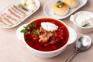 Borsch with pampushki (buns), sour cream, lard and garlic. Traditional Russian and Ukrainian soup with meat, beets, cabbage and potatoes. Close-up, selective focus.