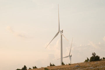 Wind turbines on a hilltop harnessing wind energy against a pale sky