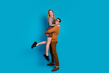 Young couple happily posing on a blue background with stylish casual wear, displaying joy and connection