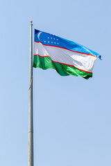 Flag of Uzbekistan on a flagpole flutters in the wind