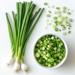 Green onions, sliced and whole, on a white background with a bowl of green onions in it