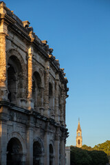 Ancient Roman amphitheatre and Church of Sainte Perpetue in Nimes at sunset, Occitanie region of southern France