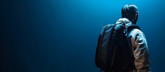 Mysterious Traveler: A Man with a Backpack Against a Deep Blue Background