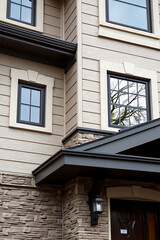Modern House Exterior: Stone and Siding Design. Contemporary home architecture with large windows and a stylish entrance. Real estate photography
