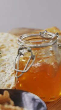 Bowl of green olives, bread, jam, rosemary herb, cheese and walnuts on wooden board