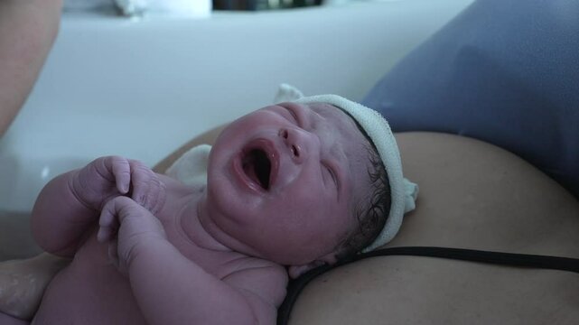 Crying newborn baby right after birth, firsts breath of an infant first seconds of life during childbirth