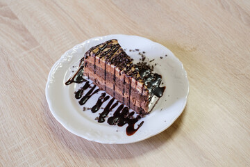 Decadent chocolate cake slice drizzled with chocolate sauce and chocolate shavings
