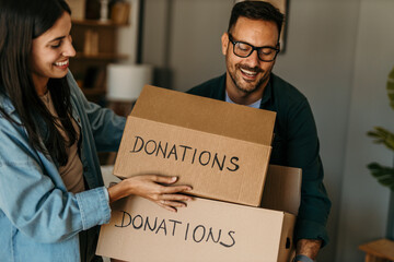 Spreading kindness. Man and woman carrying a donation box filled with clothing items