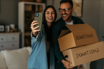 Helping others from home. Mid-aged couple taking a selfie after a sorting and boxing clothes for a...
