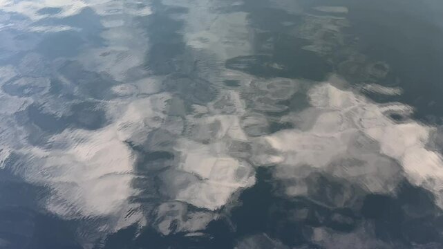 River water with reflections of clouds on surface.