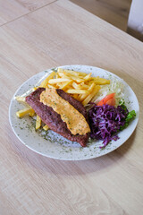 Savory grilled meat topped with creamy sauce served with fries and a fresh salad