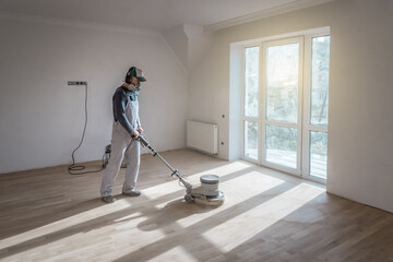 Professional worker with polishing grinding machine cleans wooden parquet floor
