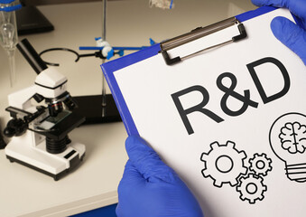 R and D as research and development concept. R&D and microscope on table
