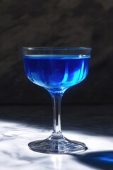 A tall blue cocktail in a stemware glass, possibly a martini or blue drink.