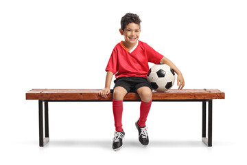 Smiling boy sitting on a bench with a football