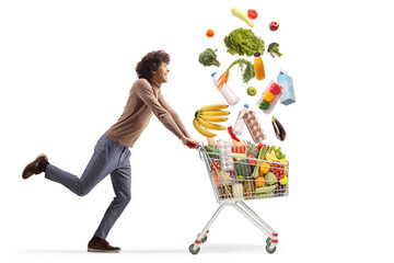 Young man running with different products falling into a shopping cart