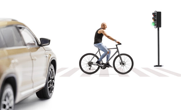 Car stopping at green traffic light and guy riding a bicycle at a pedestrian crossing