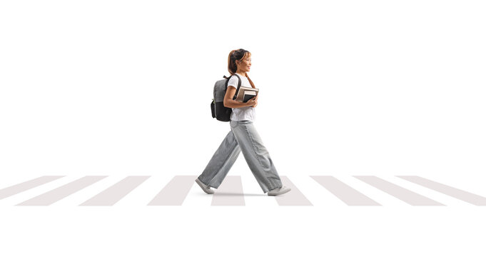 Asian female student holding books at a pedestrian zebra crossing