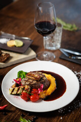 Succulent beef filet with foie gras, served with velvety mashed sweet potatoes, grilled zucchini, and cherry tomatoes. A gourmet meal in a sophisticated dining setting