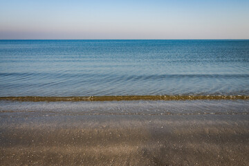 Tranquil beach with gentle sea waves under clear sky