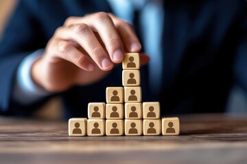 Stacked wooden blocks representing team hierarchy with silhouettes on each block, demonstrating teamwork and organizational structure in a professional setting