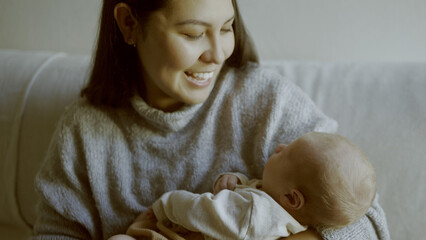 Love, mother and newborn bonding in arms for care and relax on sofa in lounge of family home with...