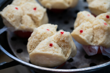Steaming basket with Huat Kueh (Chinese prosperity cakes). Light yellow, split-top cakes with red...