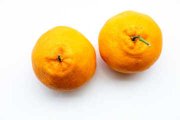Two vibrant Hallabong tangerines with prominent stems, resting on a clean white surface.