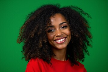 Fototapeta premium Young woman with afro hair smiling on green background