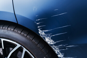 Transport accident. Deep scratch on blue car near wheel.