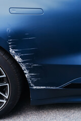 Transport accident. Deep scratch on blue car near wheel. Insurance and restoration.