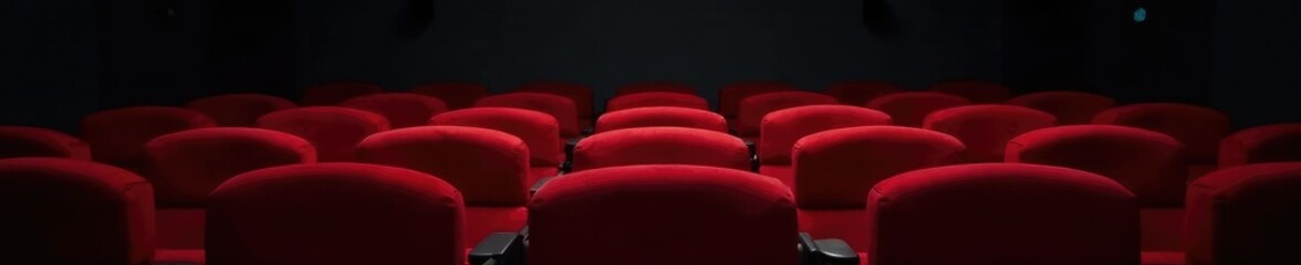 Obraz premium Single empty red theater seat against a black wall, seat, empty, desolation