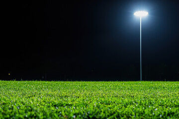 Illuminated football field at night with bright floodlights shining down