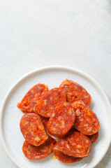 Slices of Spanish Chorizo sausage with red pepper, paprika and garlic on small plate. Traditional Mediterranean food concept. Vertical orientation. Selective focus. Top view. Copy space